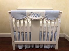 a baby crib with blue and white bedding on it's bottom rail