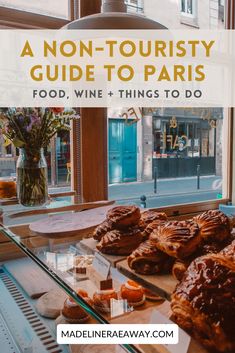 a glass case filled with pastries in front of a window and text that reads a non - touristy guide to paris food, wine & things to do