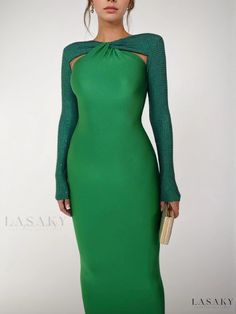 a woman wearing a green dress with long sleeves and a high neckline, standing in front of a white background