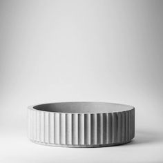 a white bowl sitting on top of a table next to a black and white wall