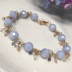 "The Hydrangea Bracelet. This luxurious piece features AAA Blue Lace Agate with beautiful swirls of powdery sky blue. Clusters of AAA periwinkle Tanzanite, creamy freshwater Pearls, white topaz and petal pink rose quartz cascade between each blue lace agate. All gemstones are faceted for maximum sparkle and shine, and everything is intricately wrapped in your choice of 14kt yellow gold filled, 14kt rose gold filled or sterling silver. A highly polished lobster claw clasp completes the design. Th Bohemian Blue Faceted Bracelet, Blue Lace Agate Jewelry, Light Blue Bracelet, Blue Lace Agate Bracelet, Tanzanite Bracelet, Cluster Bracelet, Sea Glass Bracelet, Silver Opal Ring, Blue Beaded Bracelets