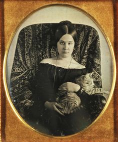 an old photo of a woman holding a cat