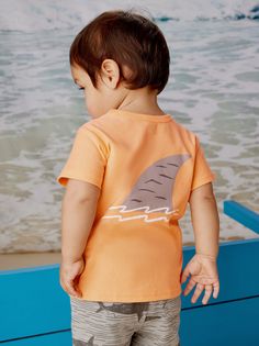 This sweet baby shark is a good reminder that most are friendly to humans. This back-to-front tee is set against a summery cantaloupe background and pairs beautifully with a shorts. Above thigh length. 100% soft cotton jersey. Standard fit Crew neckline Short sleeve Above thigh length 100% cotton jersey Machine wash Baby Graphic Tees, Kids Boutique, Tea Collection, Baby Shark, Baby Boutique, Soft Shorts, Childrens Clothes, Newborn Baby, Labour Day