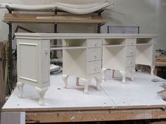 three white desks sitting on top of a piece of plywood in a room