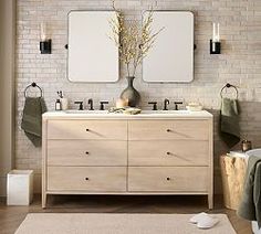 a bathroom with two sinks, mirrors and towels on the counter top in front of a brick wall