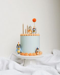 a birthday cake decorated with cartoon characters on top of a white tablecloth covered bed