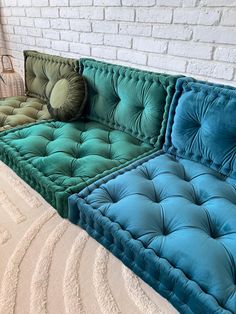 three different colored couches sitting next to each other on a carpeted floor in front of a white brick wall