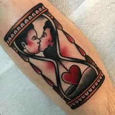 a man and woman in an hourglass tattoo on his left arm with hearts inside