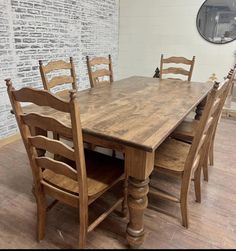 a wooden table with six chairs in front of a brick wall and hardwood flooring