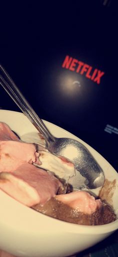 a white plate topped with meat and a spoon next to a netflix logo on a wall