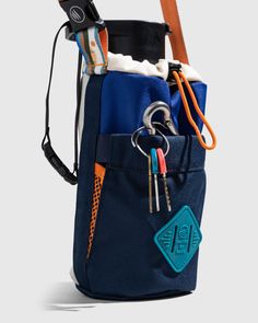 the back pocket of a blue backpack with several items in it and an orange handle