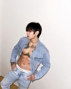 a shirtless man with tattoos on his chest standing in front of a white wall