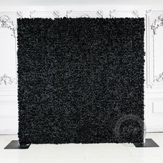 a black carpeted wall in front of a white wall