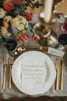 a place setting with silverware, flowers and napkins on the table in front of it