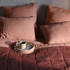 a tray with a coffee cup on top of a bed next to pillows and blankets