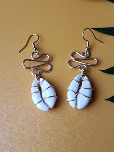 "These pretty pearl white cowrie shells are wrapped in your choice of metal wire. They are going to stand out no matter what your wearing.  Cute, earthy, lighweight and fresh. Just a funky earring for all occasions. Hangs at roughly 2\" in length. Z.A.B original." Resin Jewerly, Cowrie Shell Jewelry, Simple Ponytails, Cowrie Shells, Funky Earrings, Shell Jewelry, Cowrie Shell, Long Style, Metal Wire