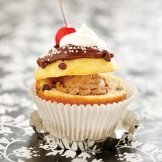 an ice cream sundae with chocolate chips and a cherry on top is sitting in a cupcake wrapper