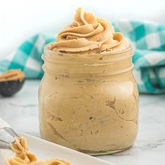 a jar filled with peanut butter on top of a white plate next to a spoon