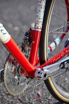 the front wheel of a red bicycle on gravel