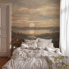 an unmade bed in front of a wall with a painting on the wall behind it