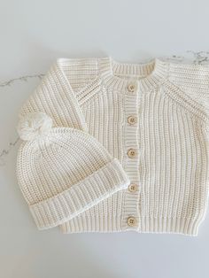 Unlock a world of warmth and comfort with this cozy Chunky Knit Cardigan! Perfect for a chilly day, it'll keep your little one snug and stylish with its traditional knit design, front buttons for convenience, and snug fit. Wrap your little one in chunky knit cuteness! Pair this cardigan with our 'Chunky Knit Beanie' Soft Knit Sweater For Playtime In Fall, Cozy Winter Sweater For Playtime, Cream Cotton Cardigan With Soft Knit, Winter Cotton Cardigan For Playtime, Winter Playtime Cotton Cardigan, White Merino Wool Knitted Cardigan, Cream Soft Knit Cotton Outerwear, Cream Cotton Outerwear With Soft Knit, White Winter Cardigan For Playtime