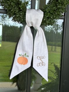 a door hanger with two pumpkins and monogrammed letters on the front