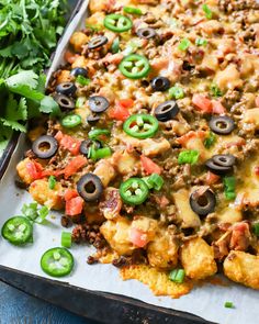 an enchilada casserole on a baking sheet with green peppers and black olives