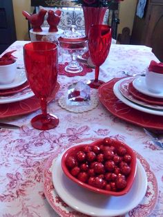 the table is set with red glassware and plates