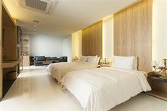 two white beds in a room with wood paneling and lights on the wall above them