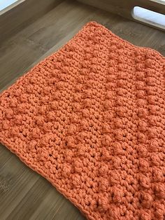 an orange crocheted blanket on the floor