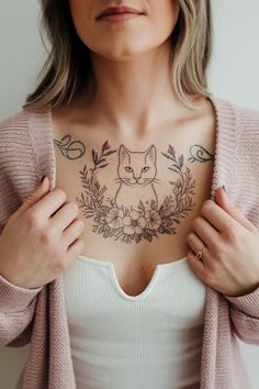 The chest tattoo combines a refined cat outline with a floral arrangement.  The flowers frame the cat’s face, adding softness and a touch of nature.  The delicate linework enhances the design’s elegance, making it both striking and graceful.  Positioned on the chest, it’s a bold choice with a gentle aesthetic.  Perfect for those who want a balance of feline charm and floral beauty. Gentle Aesthetic, Cat Outline Tattoo, Simple Elegant Style, Cat Outline, Flowers Frame, Cat S, Chest Tattoo, Animal Tattoos, Meaningful Tattoos