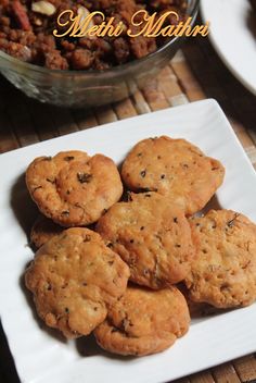 some cookies are on a white plate next to a bowl of nuts and other food