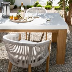 an outdoor table with two chairs and a bottle of wine on it