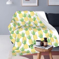 a pineapple blanket sitting on top of a wooden table next to a black couch