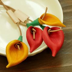 two red and yellow flowers sitting on top of a plate next to a pair of scissors