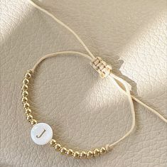 Whether you prefer an initial, a name or a phrase, this bracelet is simply a beautiful piece. Handmade with love and 2mm gold plated beads & mother of pearls initials. It is adjustable. It goes to any wrist size. Click on "Customize it" and then on the "Note" box add the letter, name or word you would like. Gold Friendship Bracelets With Letter Beads, Elegant Gold Friendship Bracelets With Letter Beads, Adjustable Gold Name Bracelet With Letter Beads, Adjustable Gold Friendship Bracelets With Letter Beads, Adjustable Personalized Pearl Bracelet For Friendship, Elegant Personalized Gold Friendship Bracelets, Adjustable White Name Bracelet With Gold Beads, Dainty Gold Friendship Bracelet With Letter Beads, Everyday Adjustable Personalized Pearl Bracelet