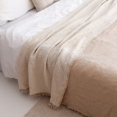 an unmade bed with white sheets and pillows