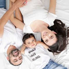 a man and woman laying on top of a bed next to a small child in a t - shirt