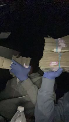 a person in blue gloves holding stacks of money