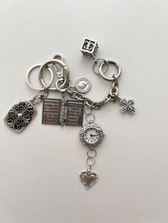 a bunch of charms that are on top of a white surface and one has a clock