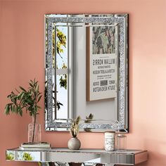 a mirror sitting on top of a table next to a vase and potted plant