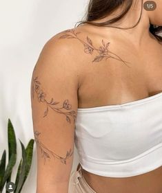 a woman with a tattoo on her arm and shoulder is standing in front of a potted plant