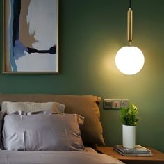 a bedroom with green walls and white pillows on the bed, next to a lamp