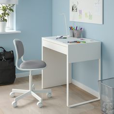 a white desk and chair in a blue room with a black bag on the floor