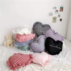 there are many pillows on the bed with one heart shaped pillow in front of them