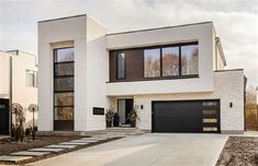 a white house with black garage doors and windows