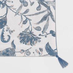 a blue and white floral print pocket with tassels on the front, featuring an olive branch