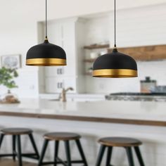 two black and gold pendant lights hanging over a kitchen island