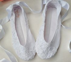 two pairs of white ballet shoes with ribbons