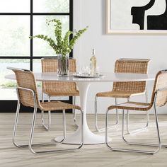 a white table with four chairs and a vase filled with flowers on top of it